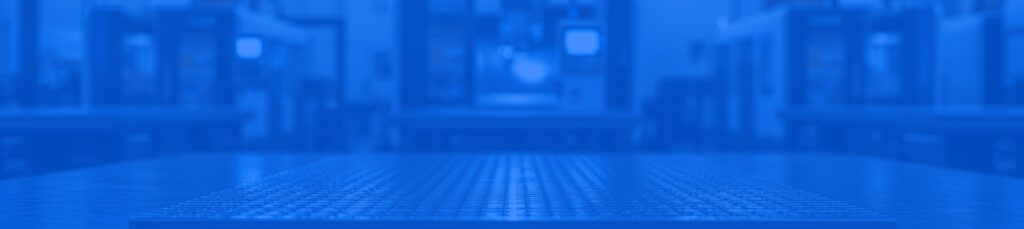 Superficie metálica de apoyo para piezas en primer plano con maquinaria de fabricación desenfocada al fondo en un taller industrial.